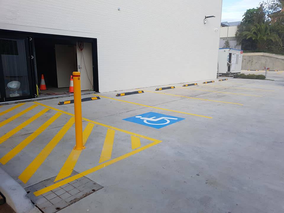Parking lot with a blue handicapped symbol on the ground and yellow lines marking spaces