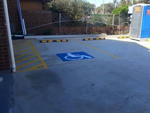 Parking lot with a blue wheelchair symbol, yellow lines, and a portable toilet.